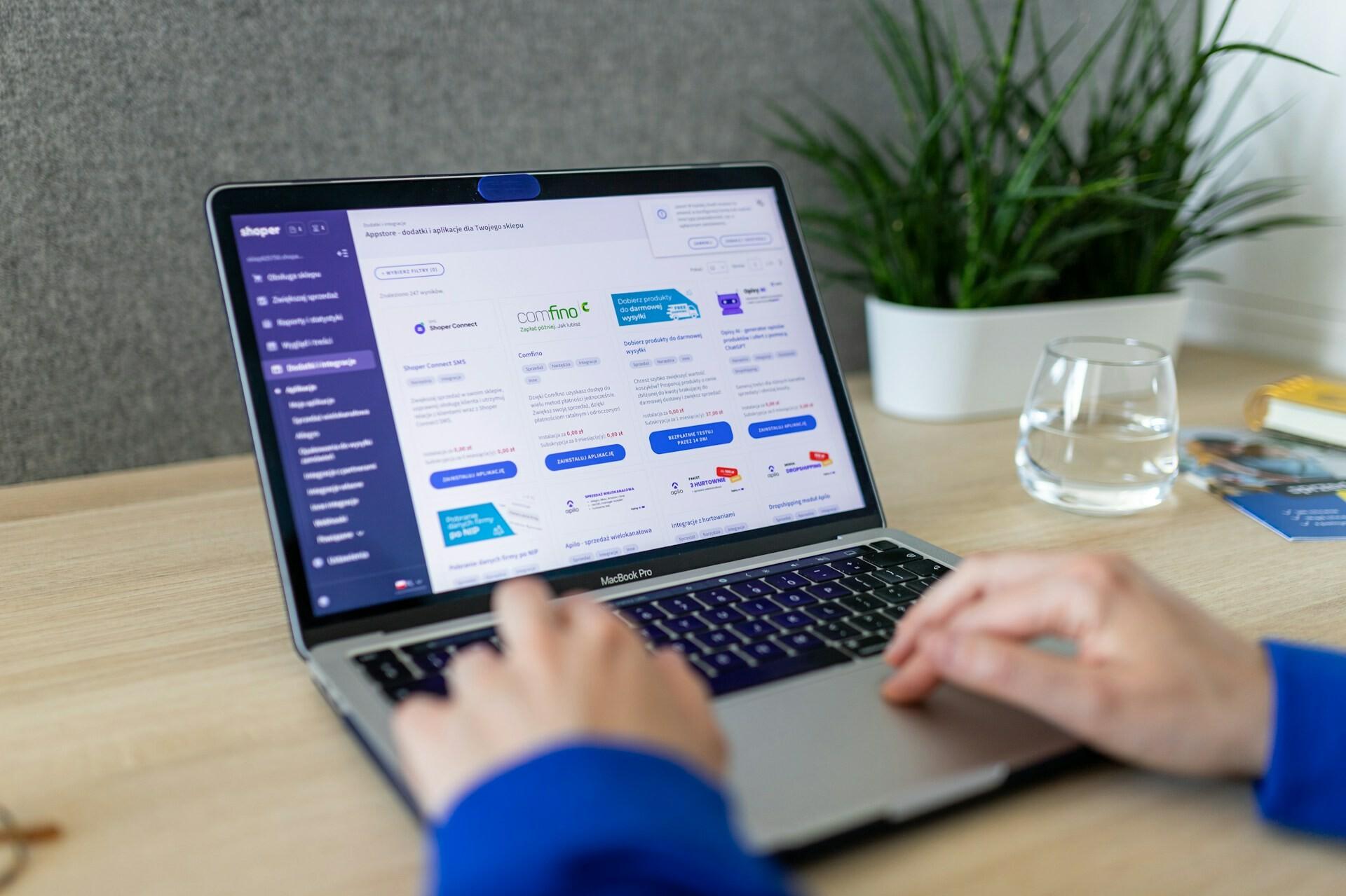 Bildschirm mit Store Zwei Hände tippen auf einem Laptop und auf dem Bildschirm ist ein Online-Shop zu sehen. 