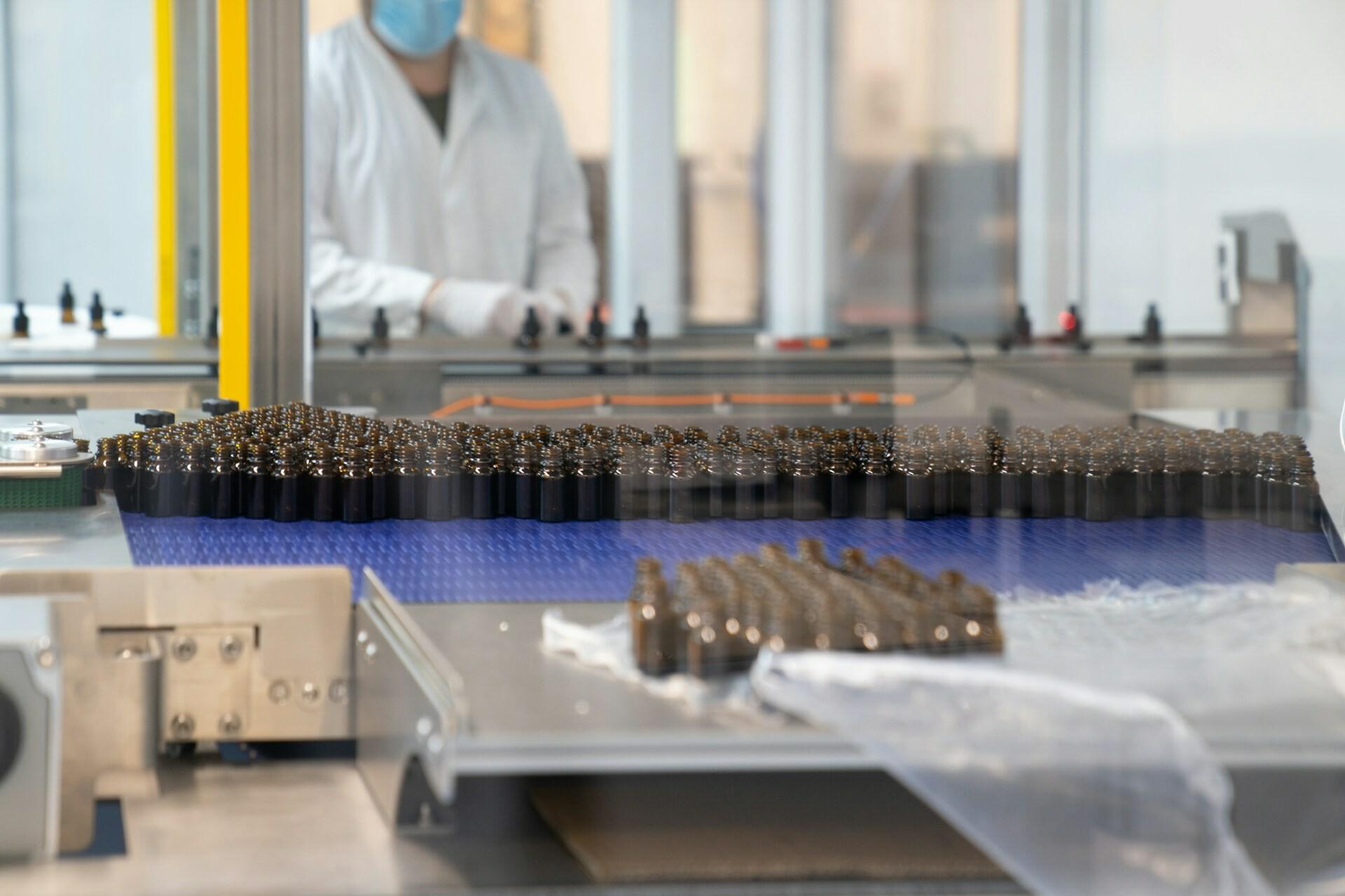 Förderband Fabrik Auf einem Förderband in einer Fabrik befinden sich mehrere Medikamenten-Fläschchen.