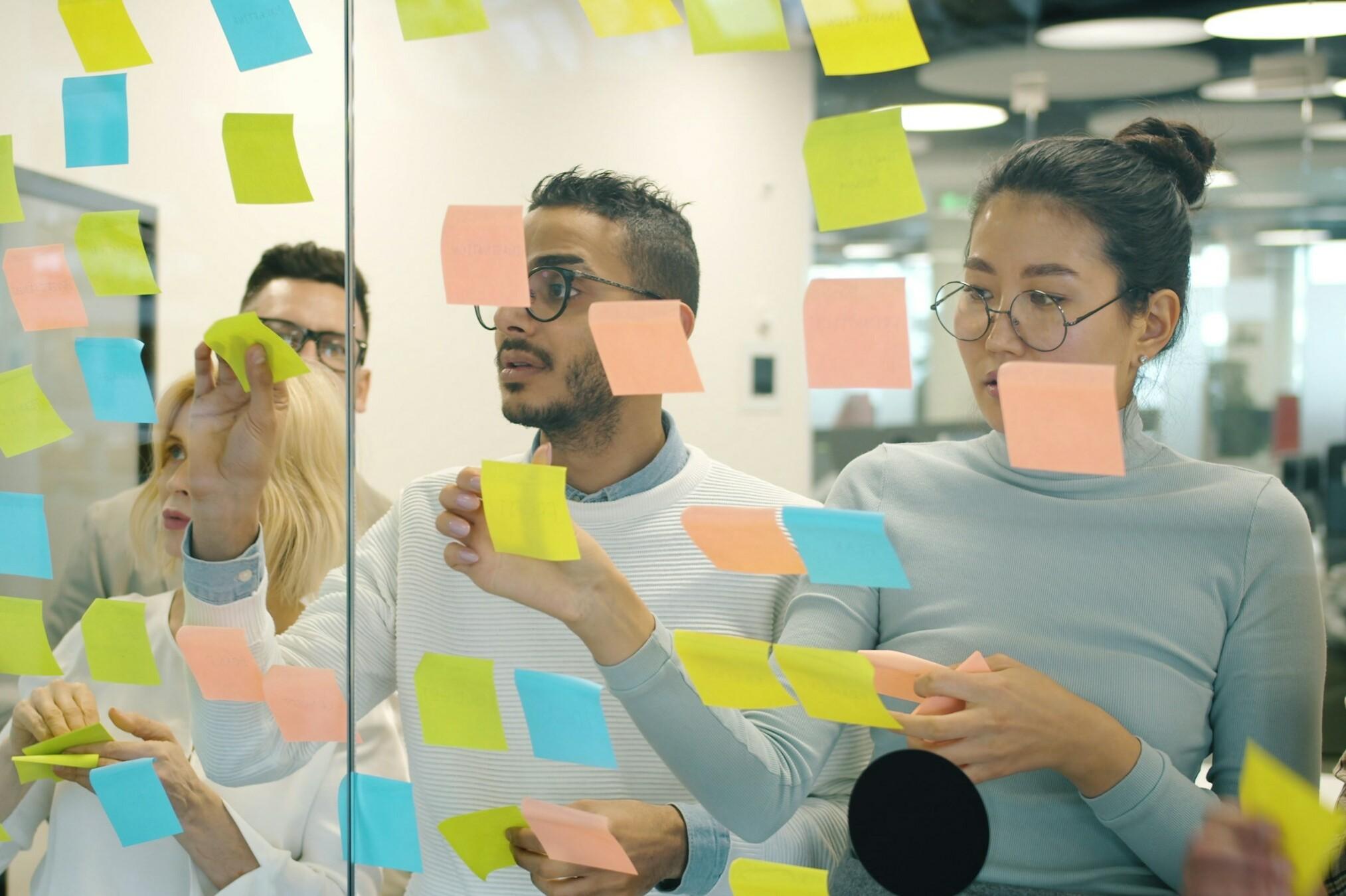 Brainstorming Mehrere Personen stehen vor einer Glaswand und brainstormen