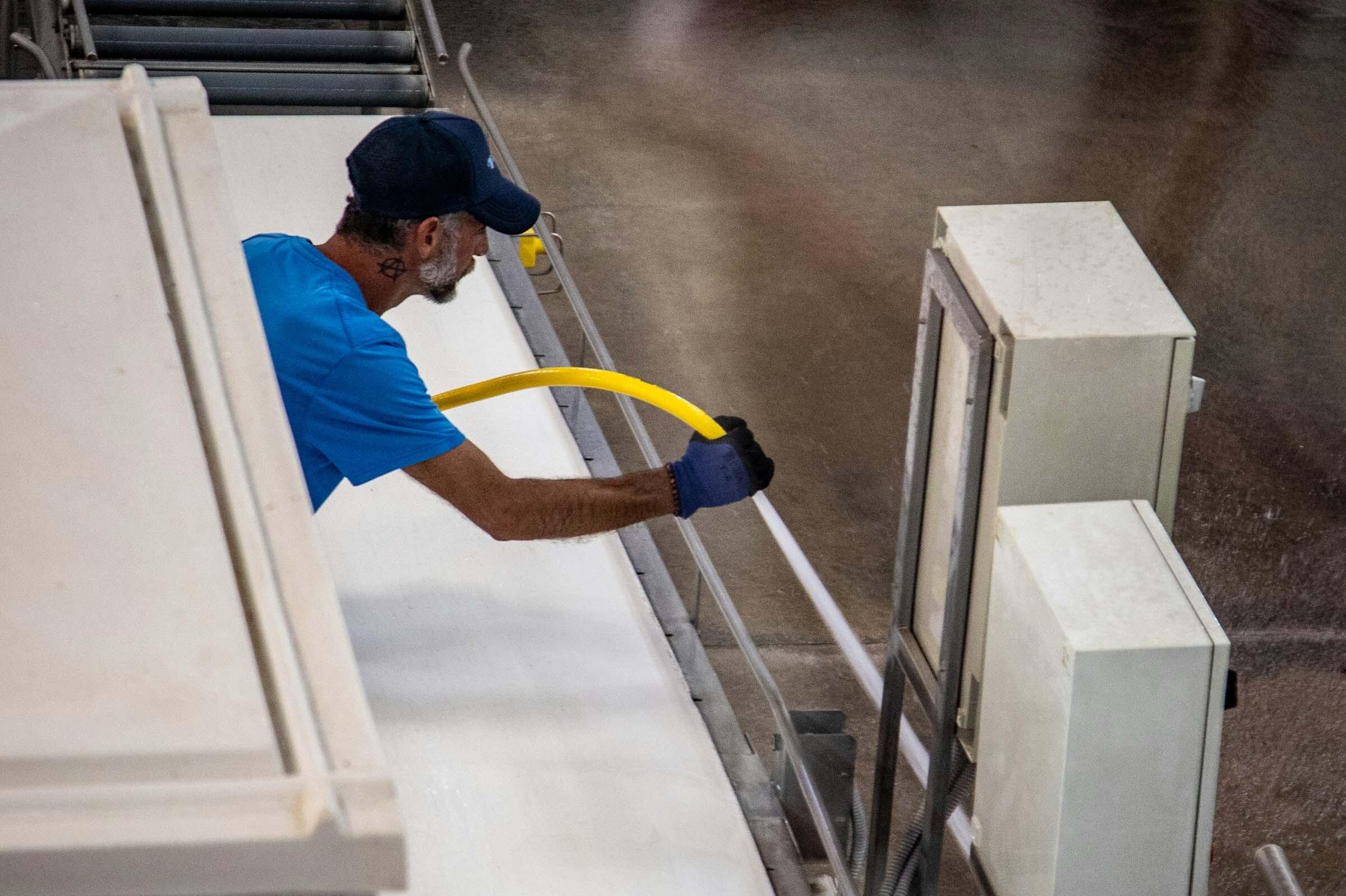 Reinigung Person reinigt ein industrielles Förderband mit einem Schlauch