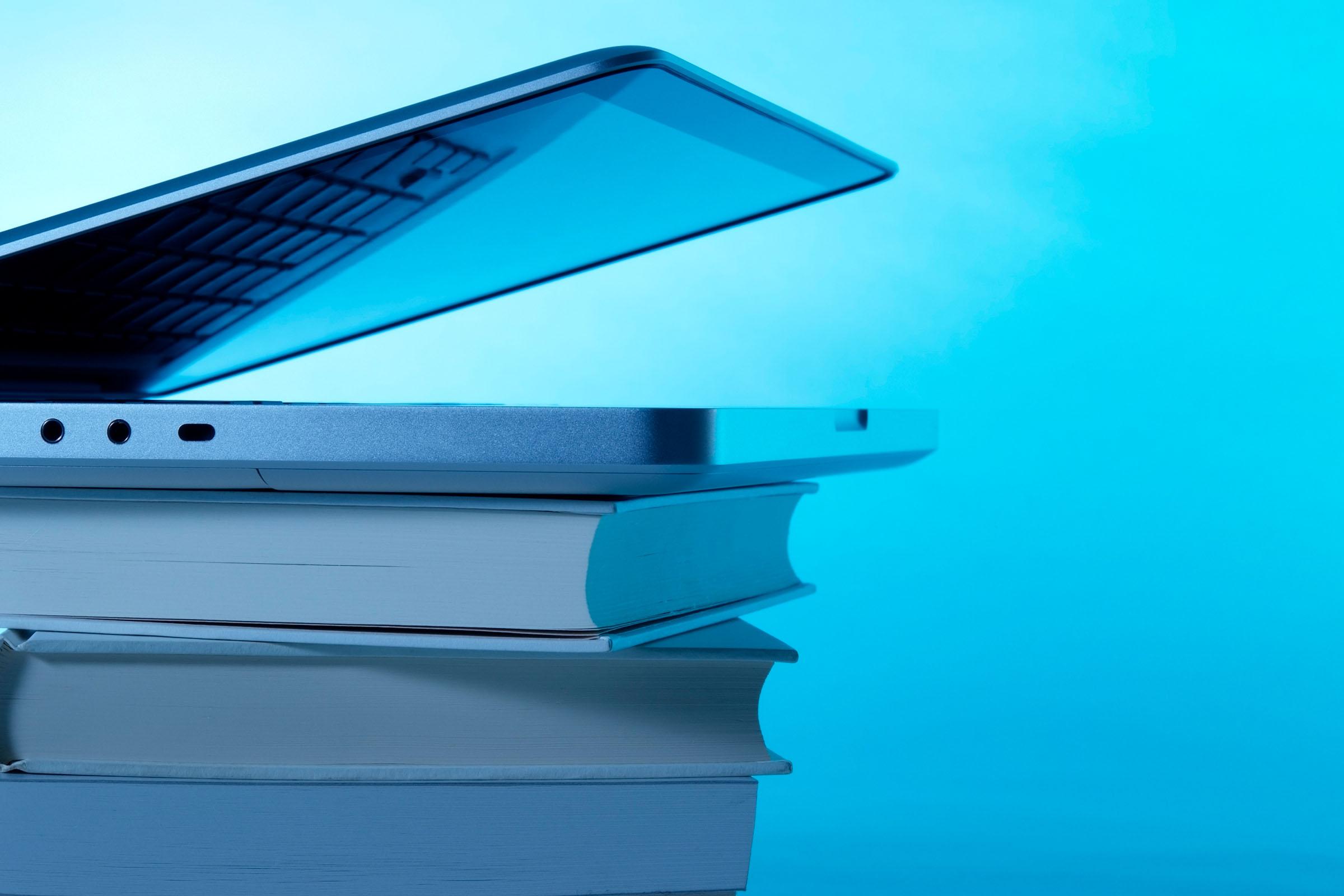 Bücher und Laptop Auf einem Stapel Bücher liegt ein halb geöffneter Laptop