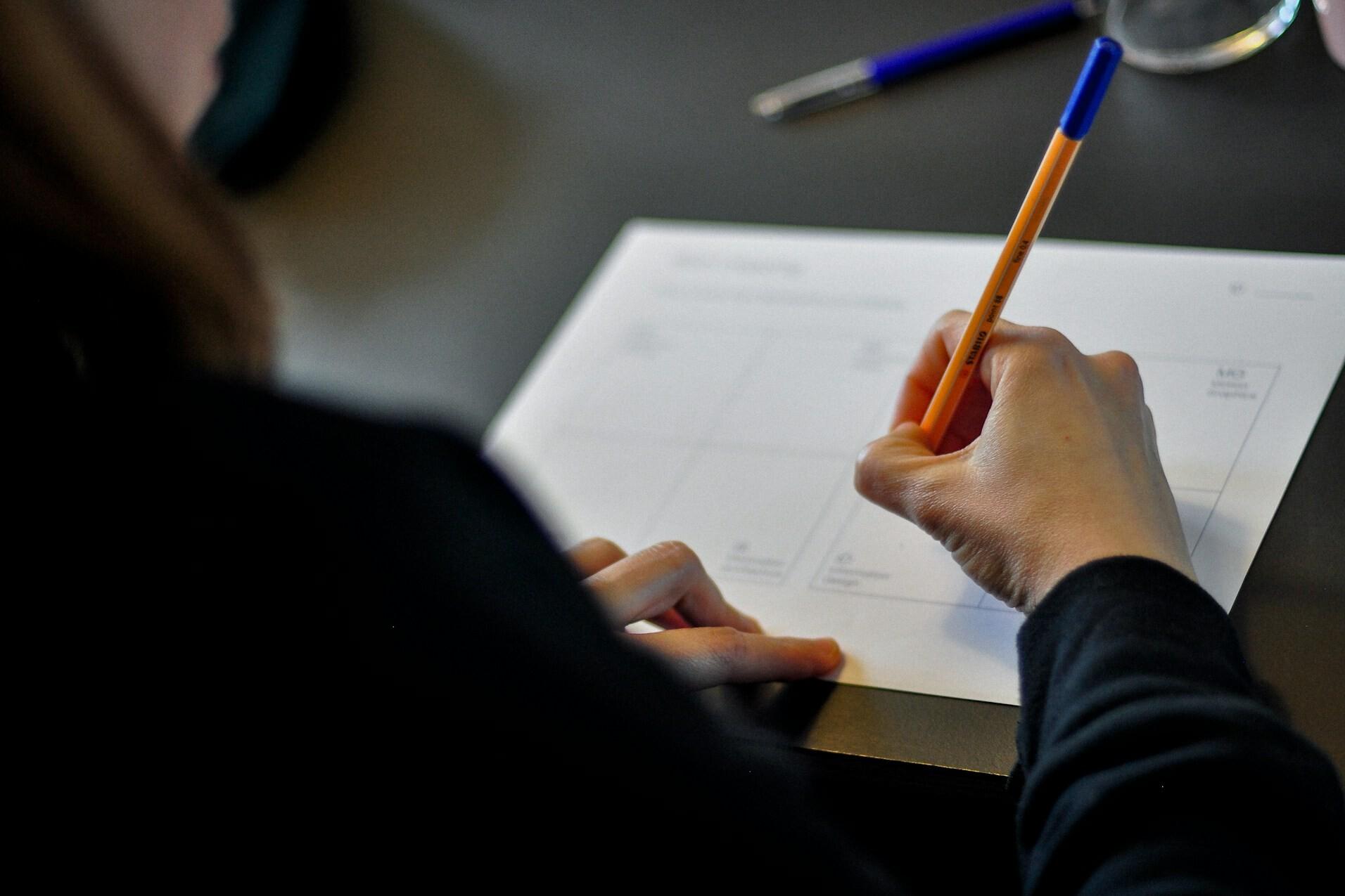 Handschriftliche Notiz A woman's hand, holding a pen, is writing something down